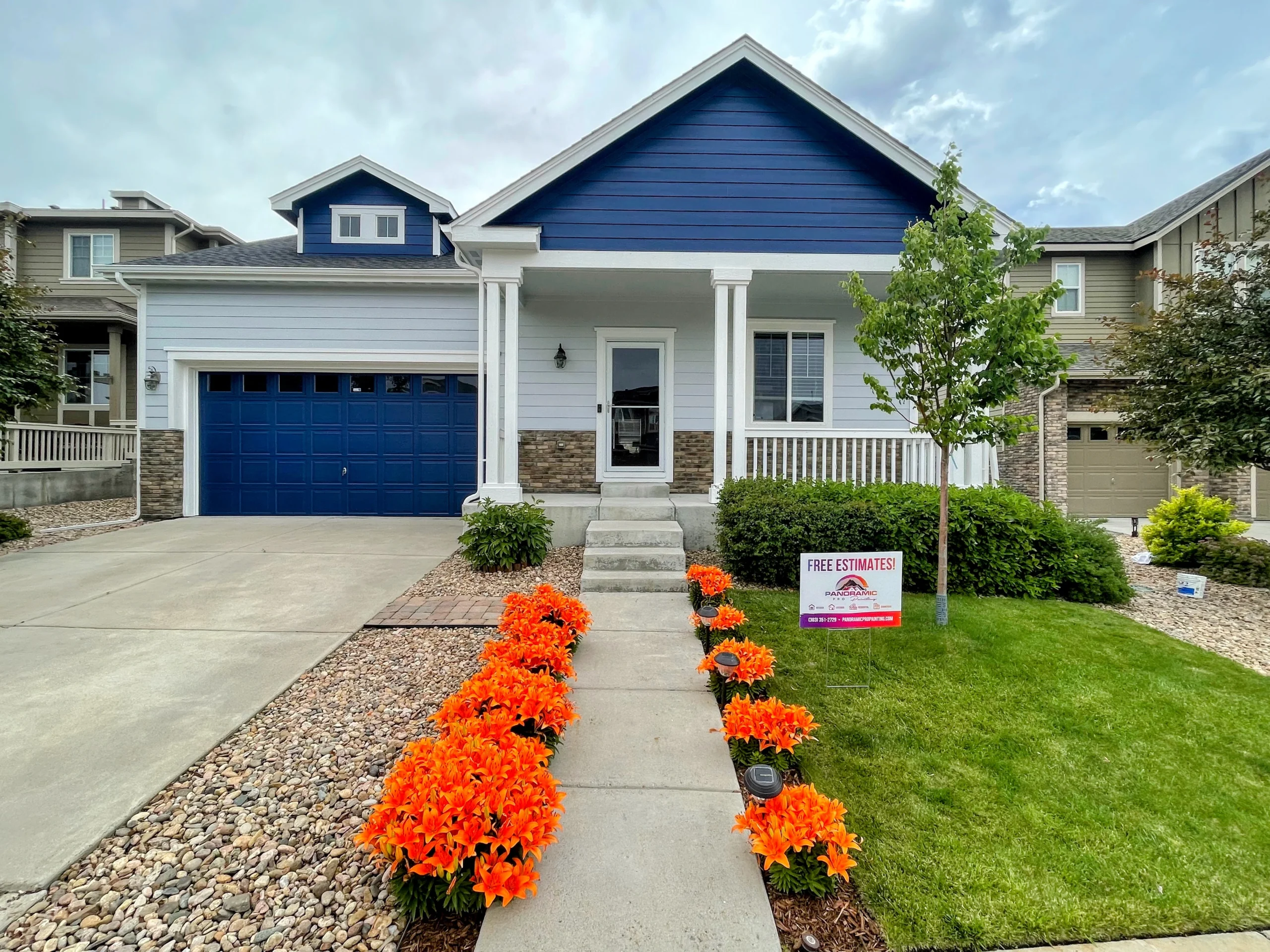 White home exterior with blue garage door, blue siding accents, and landscaped front yard