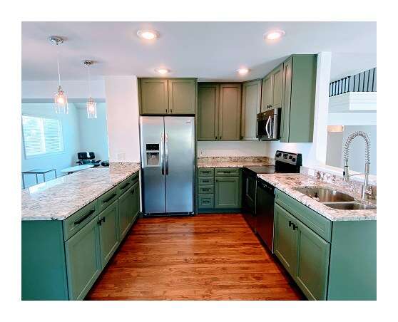 Remodeled kitchen with sage green cabinets, granite countertops, stainless steel appliances, and hardwood flooring